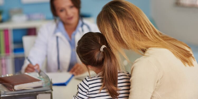 A mother and daughter confer with a doctor.