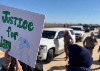 A protestor holds an anti-ICE signs during a demonstration and vigil outside the South Texas Family Residential Center in Dilley, Texas, on Jan. 28, 2026.