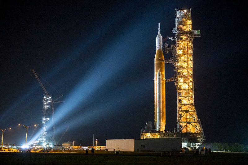 CAPE CANAVERAL, FLORIDA - MARCH 20: (EDITOR’S NOTE: This Handout image was provided by a third-party organization and may not adhere to Getty Images’ editorial policy.) In this handout image provided by NASA, NASA's Space Launch System (SLS) rocket and Orion spacecraft, secured to the mobile launcher, is seen as it rolls out of the Vehicle Assembly Building to Launch Pad 39B, Friday, March 20, 2026, at NASA's Kennedy Space Center in Florida. NASA's Artemis II test flight will take Commander Reid Wiseman, Pilot Victor Glover, and Mission Specialist Christina Koch from NASA, and Mission Specialist Jeremy Hansen from the CSA (Canadian Space Agency), around the Moon and back to Earth with launch opportunities beginning in April 2026. (Photo by Aubrey Gemignani/NASA via Getty Images)