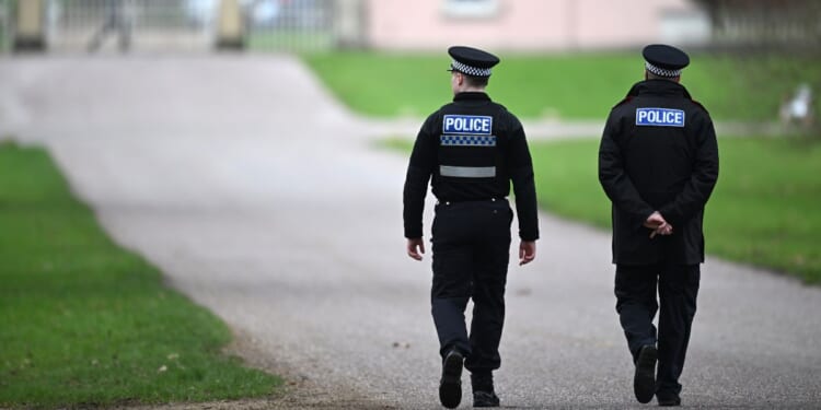 Police officers approach the gates of the Royal Lodge, Andrew Mountbatten-Windsor's former residence in Windsor Great Park, on Feb. 20, 2026, in Windsor, England.