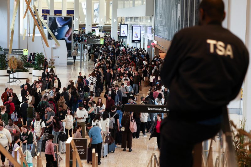 A Transportation Security Administration (TSA) agent looks on passengers queue to go through security at New York's LaGuardia airport on March 22, 2026. Immigration agents will be deployed in US airports beginning March 23, aiming to alleviate soaring congestion at security screenings amid a weeks-long budget standoff over President Donald Trump's mass deportation drive, officials said. Trump announced the extraordinary move in a social media post Sunday morning, sending officials racing to quickly develop a plan. (Photo by CHARLY TRIBALLEAU / AFP via Getty Images)