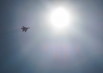 LAKENHEATH, ENGLAND - APRIL 17: A US Air Force F-15 Strike Eagle fighter aircraft is silhouetted by the sun as protesters stage a peaceful demonstration outside RAF Lakenheath on April 17, 2025 in Lakenheath, England. From 1981, a group of women supporting the Campaign for Nuclear Disarmament (CND) held a peace camp at RAF Greenham Common, which eventually led to the removal of US nuclear weapons from the military base in 1988. Some of the same women are at the peace camp outside RAF Lakenheath today after reports that a secret deal with the United States has been struck to once again house American nuclear weapons on British soil. (Photo by Dan Kitwood/Getty Images)