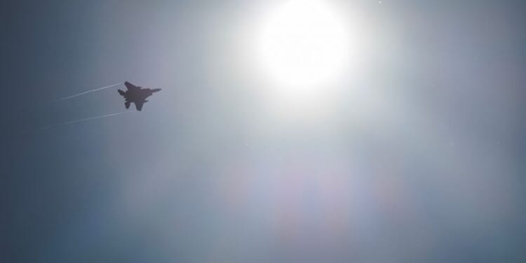 LAKENHEATH, ENGLAND - APRIL 17: A US Air Force F-15 Strike Eagle fighter aircraft is silhouetted by the sun as protesters stage a peaceful demonstration outside RAF Lakenheath on April 17, 2025 in Lakenheath, England. From 1981, a group of women supporting the Campaign for Nuclear Disarmament (CND) held a peace camp at RAF Greenham Common, which eventually led to the removal of US nuclear weapons from the military base in 1988. Some of the same women are at the peace camp outside RAF Lakenheath today after reports that a secret deal with the United States has been struck to once again house American nuclear weapons on British soil. (Photo by Dan Kitwood/Getty Images)