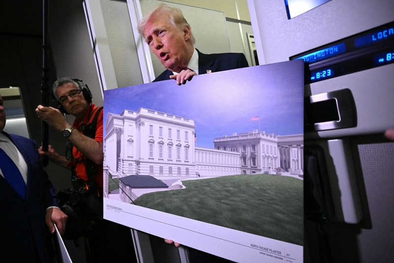 US President Donald Trump holds a rendering of the East Wing modernization as he speaks to reporters aboard Air Force One en route to Joint Base Andrews, Maryland, on March 29, 2026. President Donald Trump said March 29 the US military was planning a large complex beneath the new ballroom he is building at the White House. "The military is building a massive complex under the ballroom, and that's under construction, and we're doing very well, so we're ahead of schedule," Trump told reporters aboard Air Force One, returning to White House after spending the weekend at his Mar-A-Lago residence. (Photo by Mandel NGAN / AFP via Getty Images)