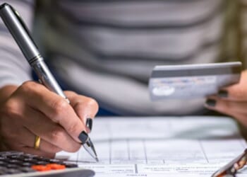 Woman looks at card and writes on a form.