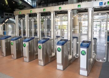 Row of stainless steel fare gates with glass barriers and accessibility icons ar seen Oct. 15 at the BART transit station entrance in South San Francisco, California.
