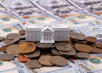 Miniature symbolic residence of the US President - White House on a stack of American coins and bills