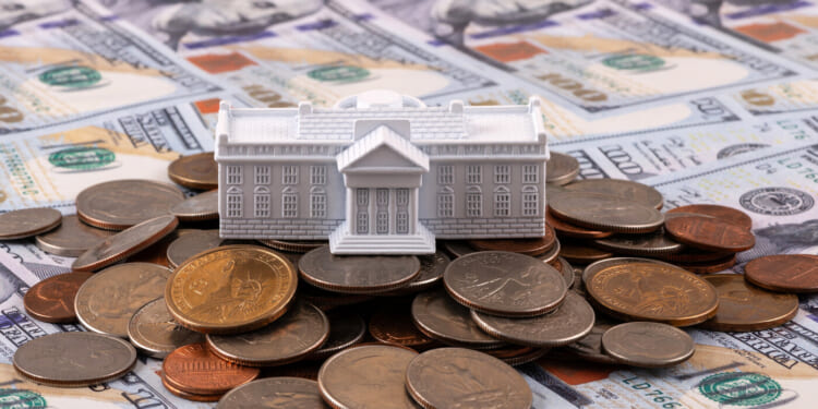 Miniature symbolic residence of the US President - White House on a stack of American coins and bills