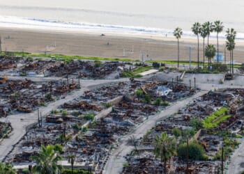 An American flag and sand bag stands on a cliff overlooking the remains of the Pacific Palisades Bowl Mobile Estates, which was destroyed in the 2025 Palisades fire, on the one year anniversary in Pacific Palisades on Jan. 6, 2026.
